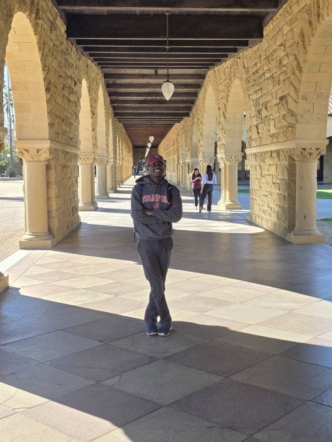 Jonas Ngnawé wearing a Stanford sweatshirt beneath the Main Quad arches.
